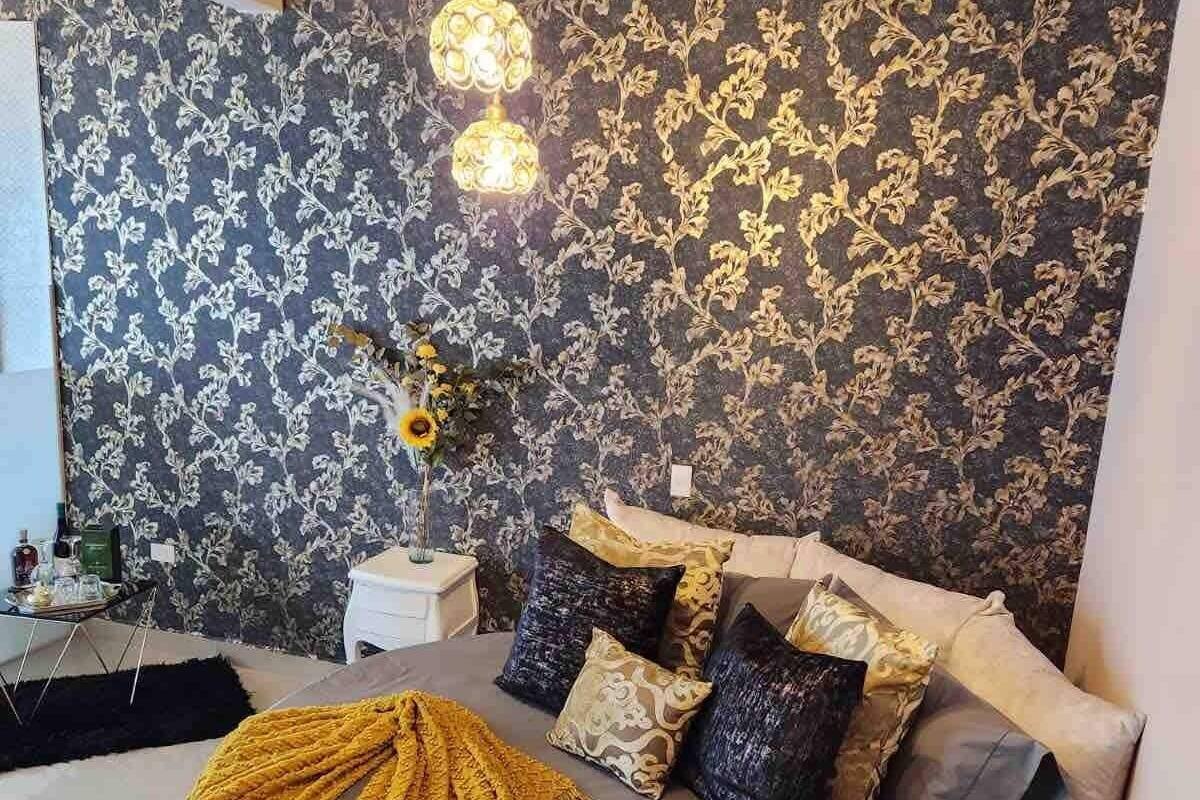 Une chambre à coucher moderne avec un lit rond, un papier peint à motifs et un éclairage décoratif.