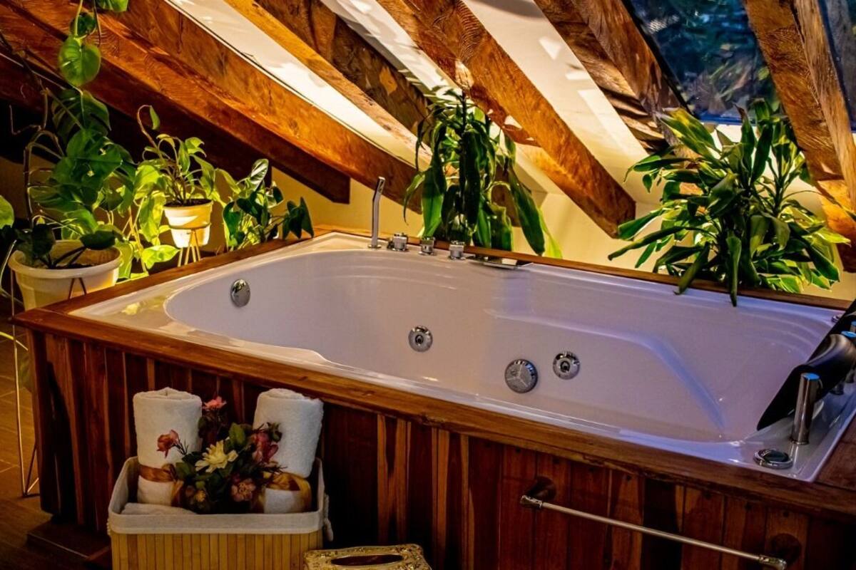 Une grande baignoire dans une pièce avec des poutres en bois et des plantes en pot.