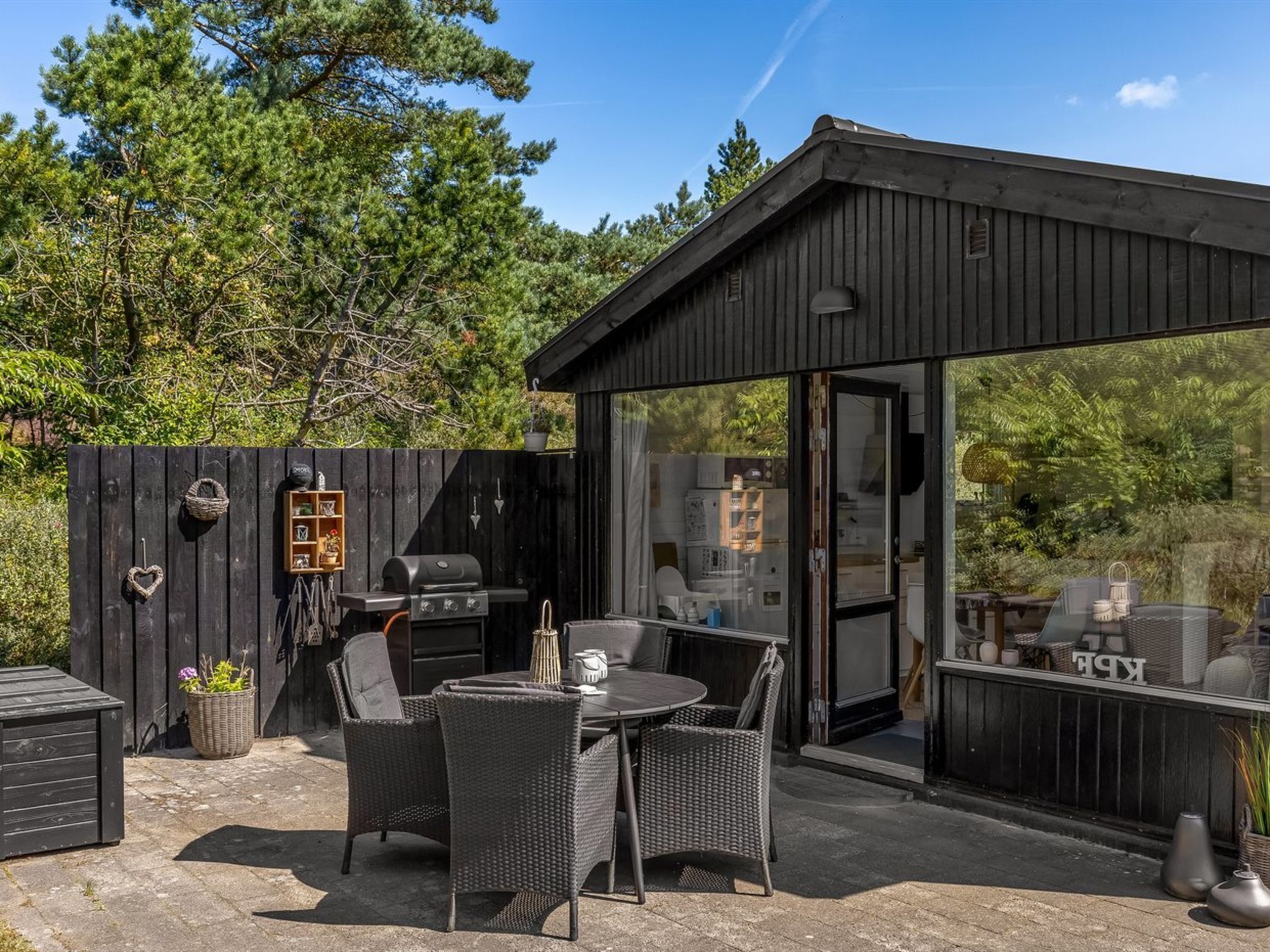 Patio esterno con tavolo e sedie, un barbecue e una recinzione in legno.