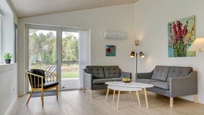 A modern living room with a grey sofa, a round coffee table, and a wooden chair. There is a painting on the wall and a floor lamp. - "Alona" - 250m from the sea by Interhome (Jerup)