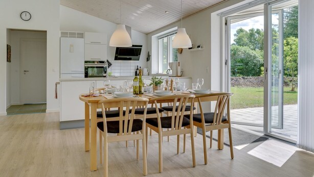 A modern kitchen with white cabinets, a built-in oven, and a dining area with a wooden table and chairs. - "Alona" - 250m from the sea by Interhome (Jerup)