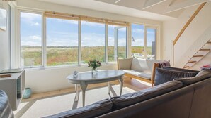 A modern interior with a large window, a sofa, a small table, and a staircase. - "Helga" - 800m from the sea by Interhome (Skagen)