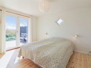 Een slaapkamer met een bed, dakraam en uitzicht op een terras.