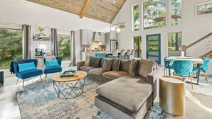 A spacious living area with a large sectional sofa, a coffee bar, and a dining area with teal chairs.