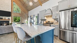 A modern kitchen with a large island, stainless steel appliances, and a blue accent wall.