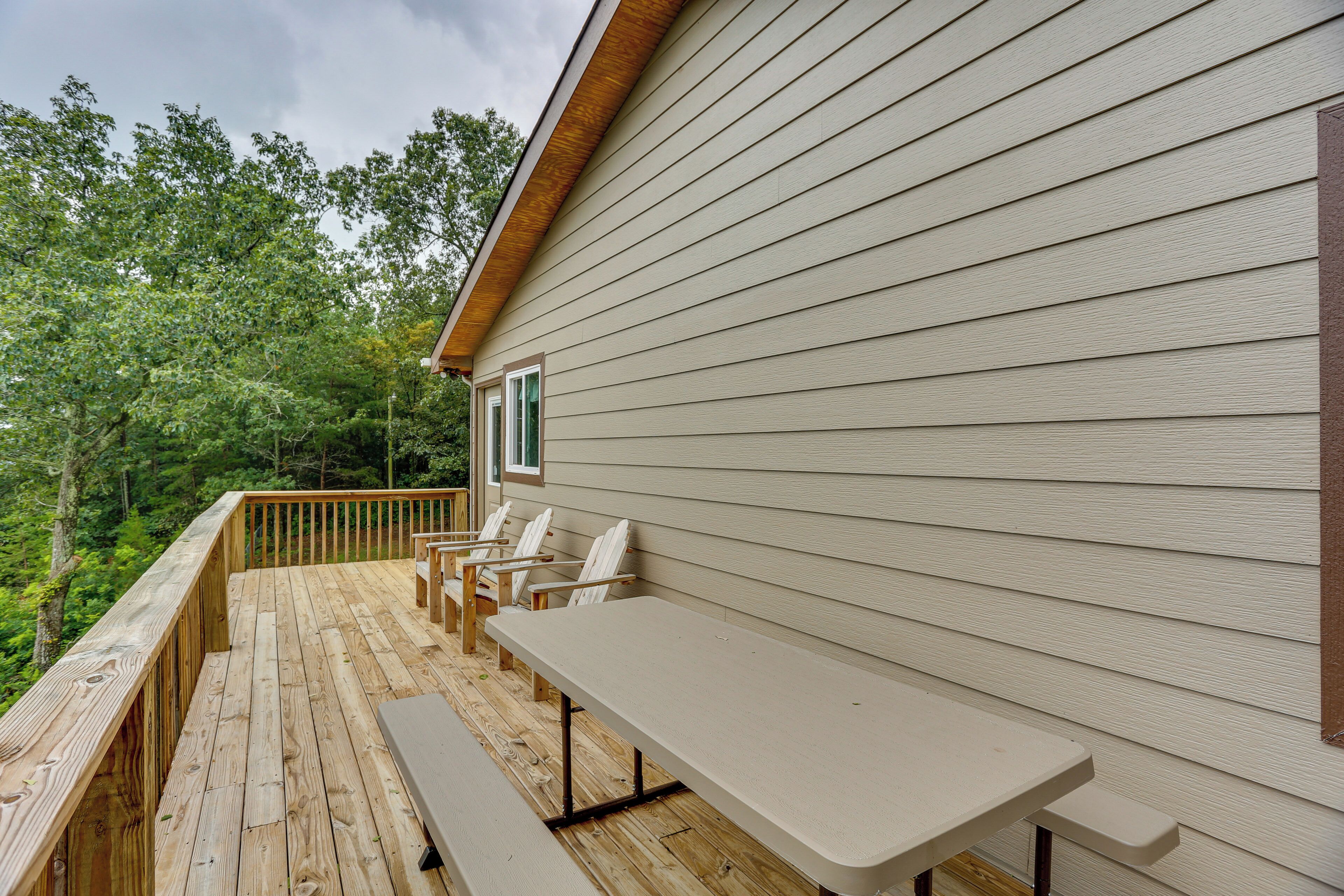 A wooden deck with a table and chairs, overlooking a forested area.