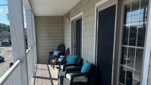 A covered outdoor seating area with wicker furniture and a blue patterned mat.