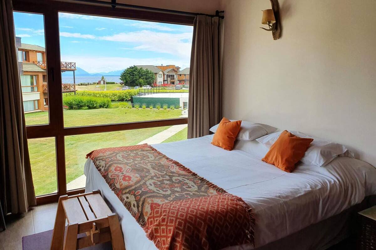 Una habitación de hotel con una cama grande, vistas al exterior y una mesa de madera.