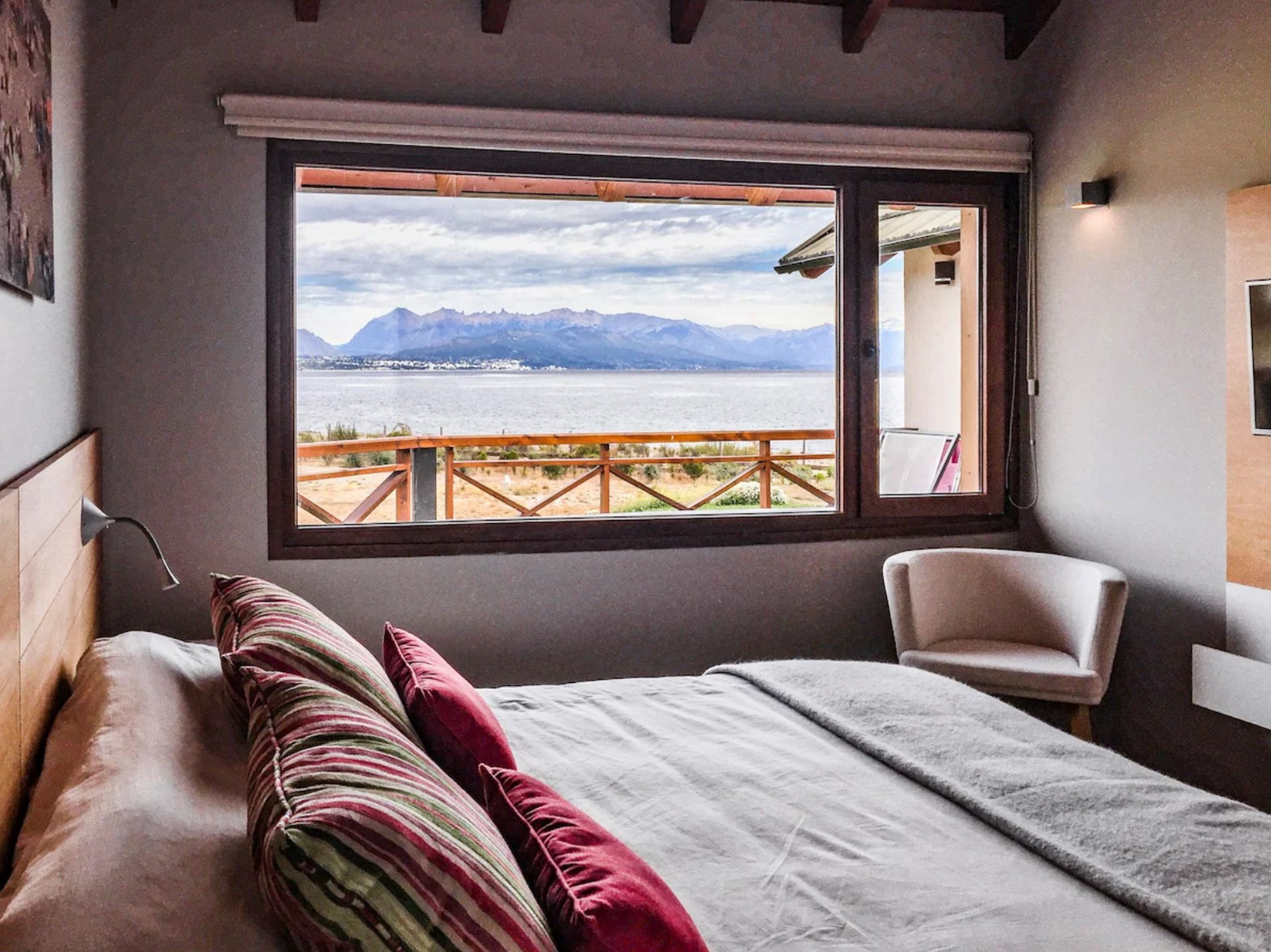 A bedroom with a large window overlooking a beach and mountains.
