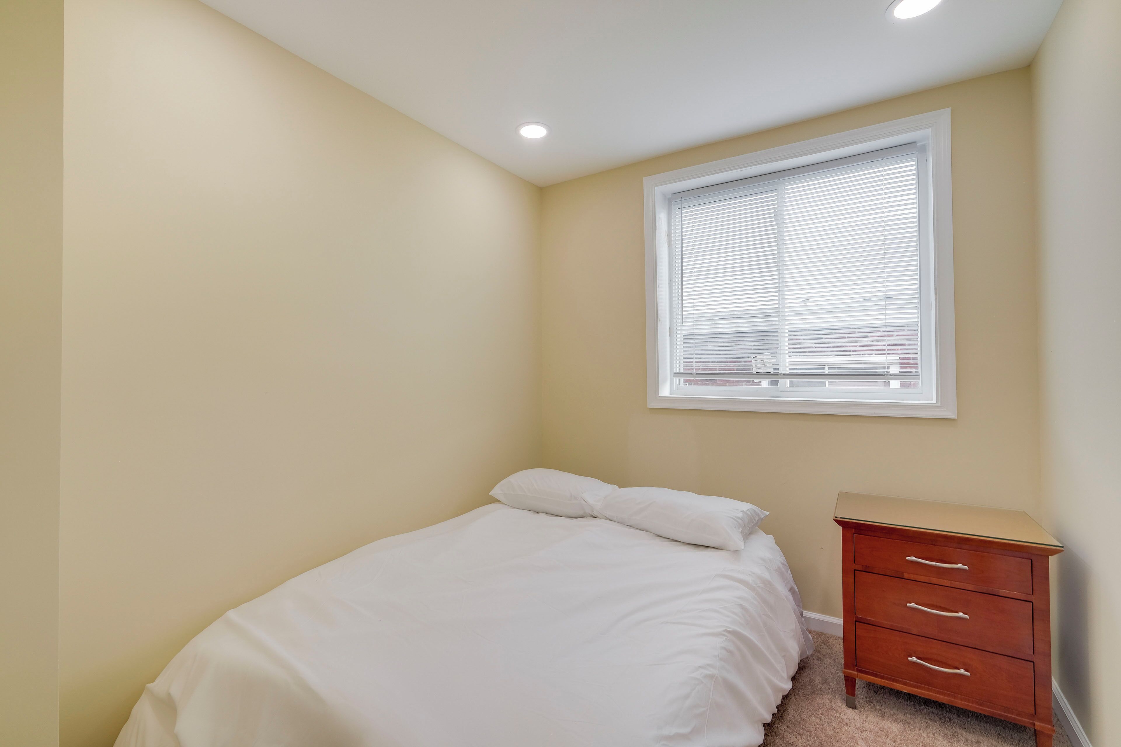 Un dormitorio con una cama individual, una mesita de noche y una ventana con persianas.