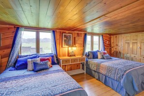 Une cabine avec deux lits, un plafond en bois, une fenêtre avec des rideaux et une table de chevet avec une lampe.