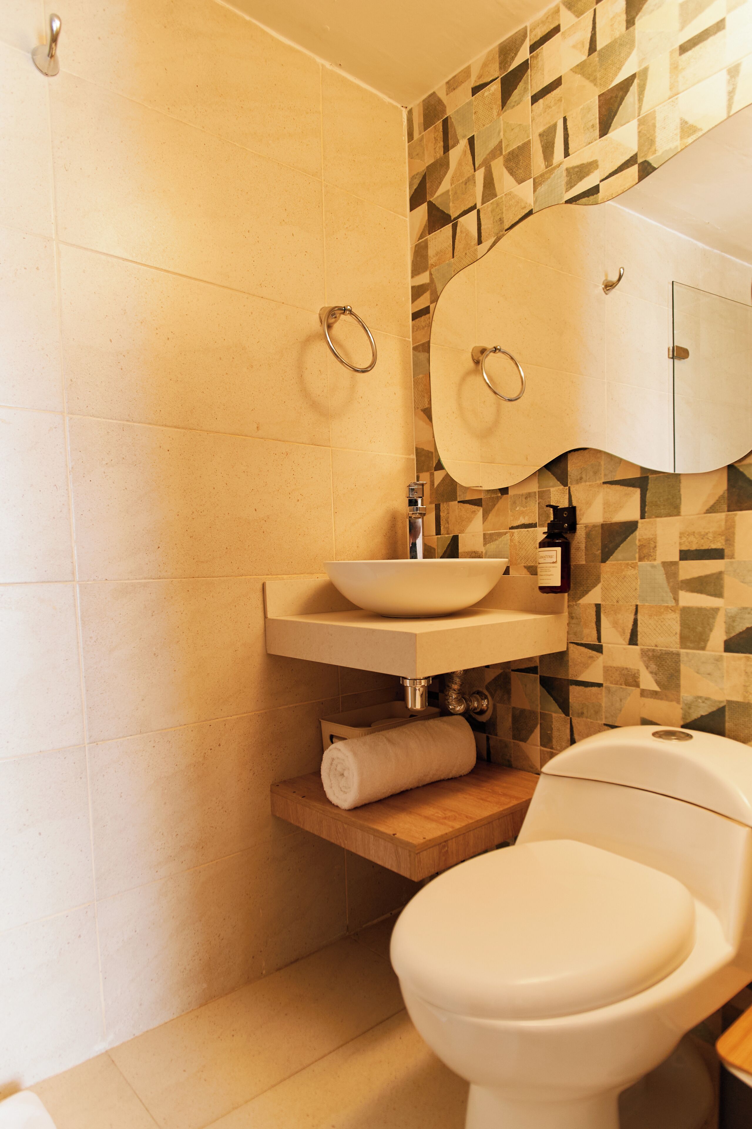 Een badkamer met een wit toilet, een wastafel met een spiegel erboven en een behangen muur.