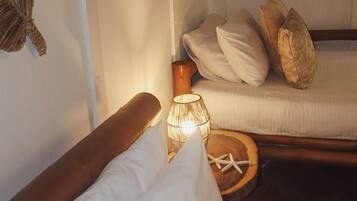 Un lit avec une literie blanche, une tête de lit en bois et une lampe de chevet.
