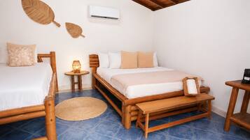 A room with a bed, a bedside table, a lamp, a small table with a coffee maker, and an air conditioner.