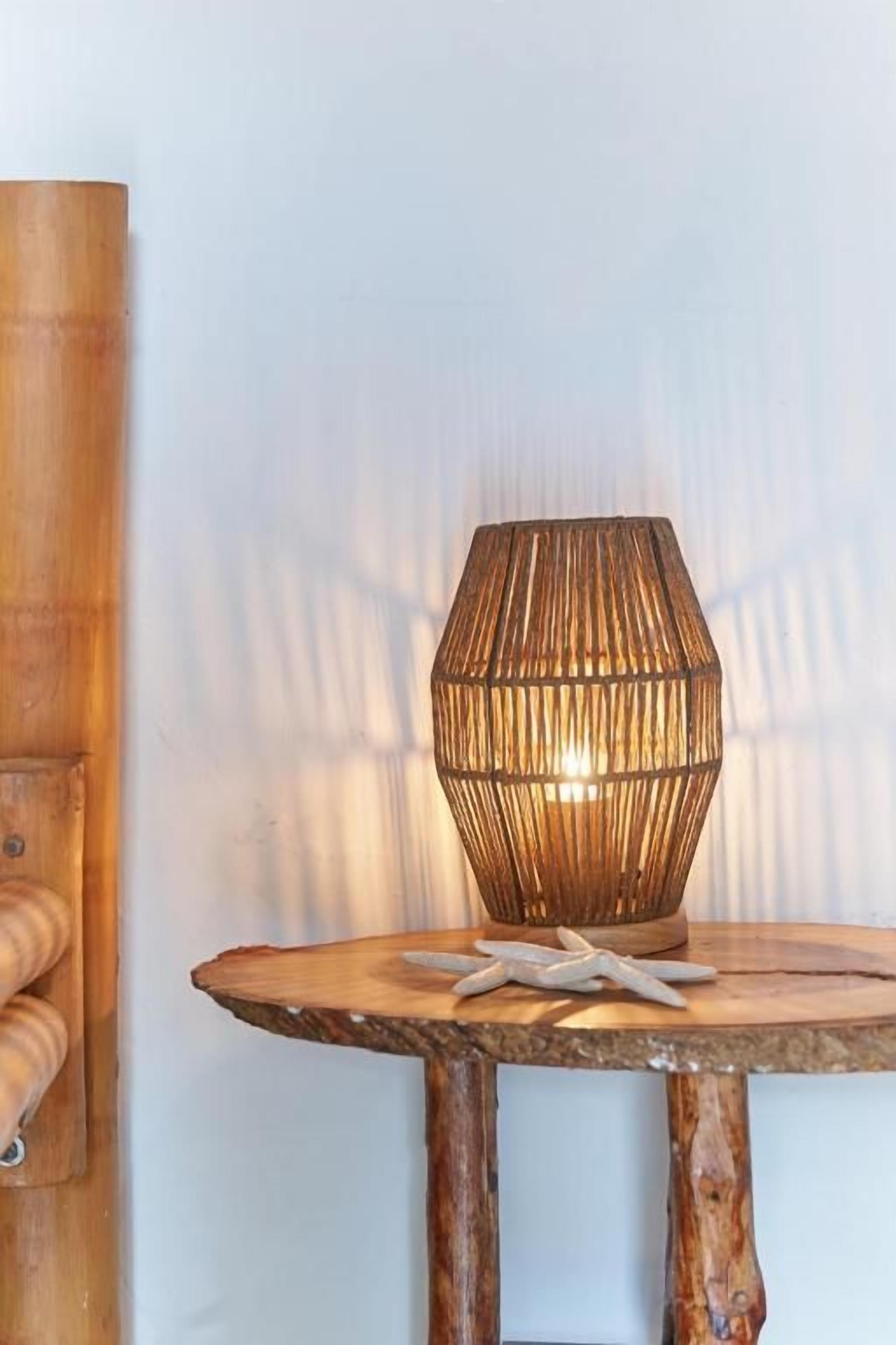 A round wooden table with a woven lamp on top, a starfish decoration, and a wooden wall panel.
