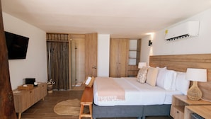 A bedroom with a bed, bedside tables, a TV, a wardrobe, and a shower area.