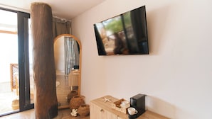 A modern room with a wooden cabinet, a coffee maker, starfish decorations, and a flat-screen TV mounted on the wall.