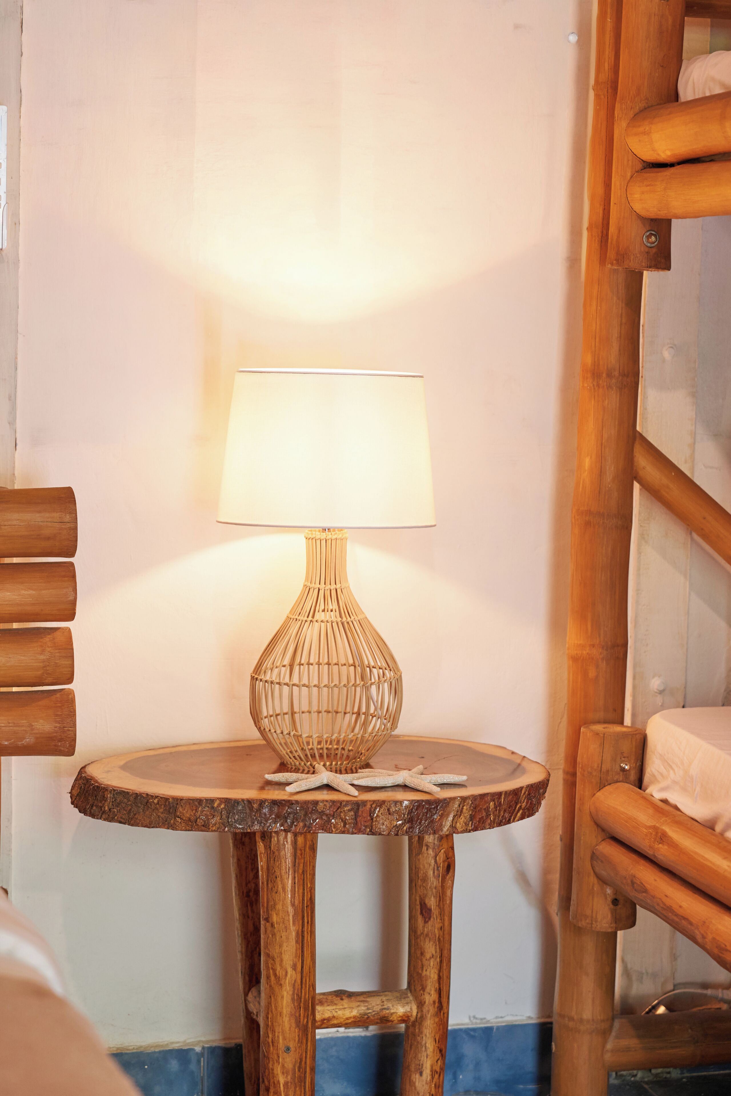 A wooden table with a woven lamp, a basket, and a starfish on the table.