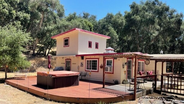 Ein zweistöckiges Haus mit einer Terrasse und Sitzgelegenheit im Freien.