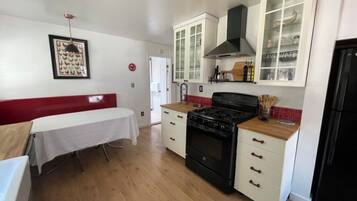 A kitchen with white cabinets, a black stove, and a wooden countertop.
