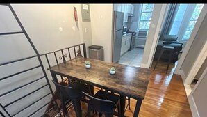 A dining area with a wooden table and four chairs, a fire extinguisher on the wall, and a view of the kitchen and living area through an open door. - Charming 2-bedroom apartment in lovely Brooklyn, 20mins to Manhattan (Brooklyn)