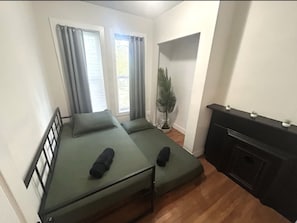 A compact room with two single beds, a small desk, and a potted plant.