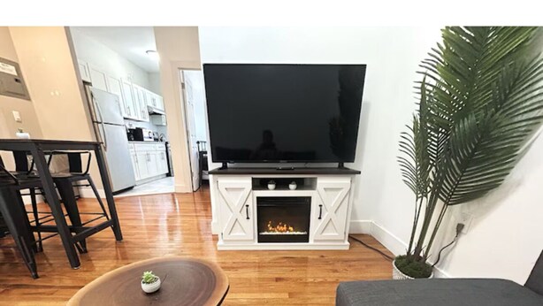 A living room with a flat-screen TV, a round coffee table, a gray sofa, and a potted plant. - Charming 2-bedroom apartment in lovely Brooklyn, 20mins to Manhattan (Brooklyn)