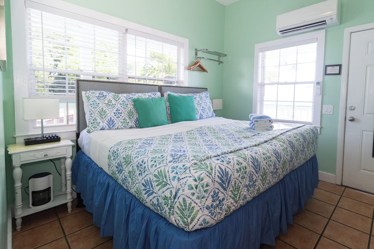 A bedroom with a bed, bedside table, and an air conditioning unit.