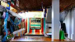 Una zona de bar con mostrador de madera, decoraciones coloridas y un cartel con texto motivacional alusivo al océano.