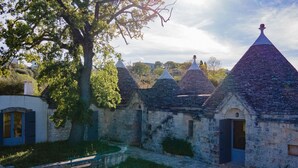 Un bâtiment en pierre doté de plusieurs toits coniques, un arbre et un sentier.