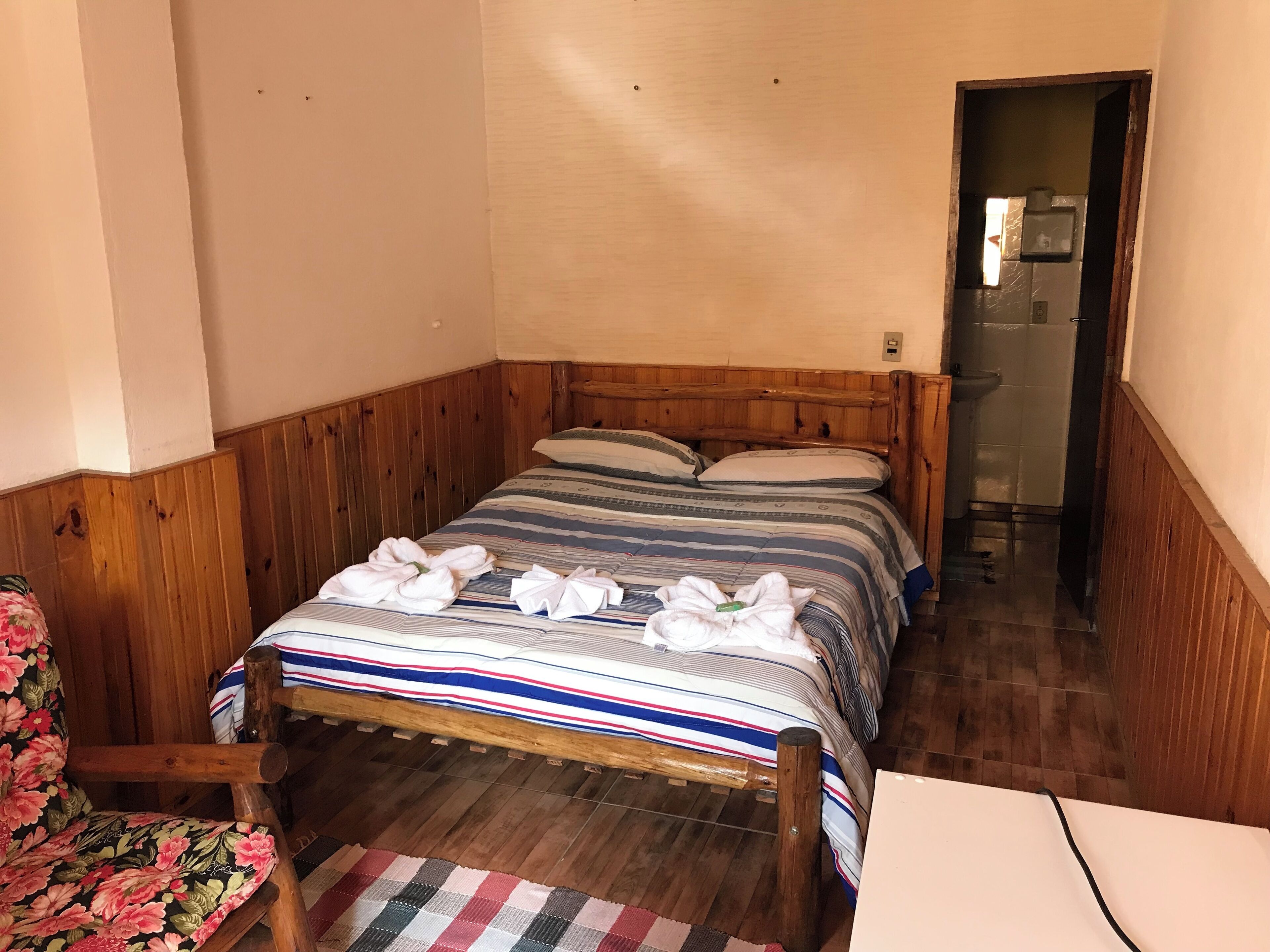Ein hölzernes Bett mit gestreifter Bettwäsche und darauf drapierten Handtüchern.