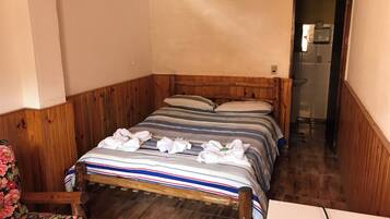 Ein hölzernes Bett mit gestreifter Bettwäsche und darauf drapierten Handtüchern.