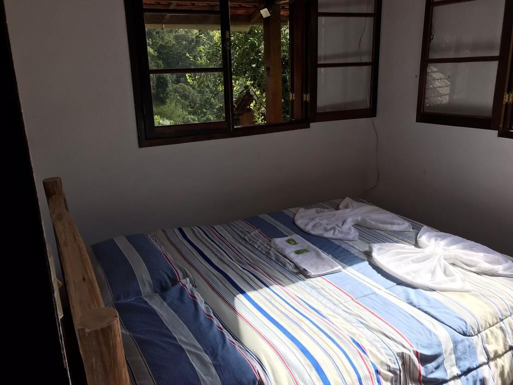 A single bed with striped bedding, a wooden headboard, and two windows with frosted glass panes.