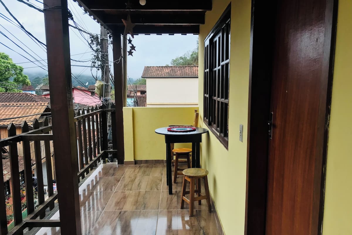 A balcony with a tiled floor, a small round table with a chair, and a wooden door.