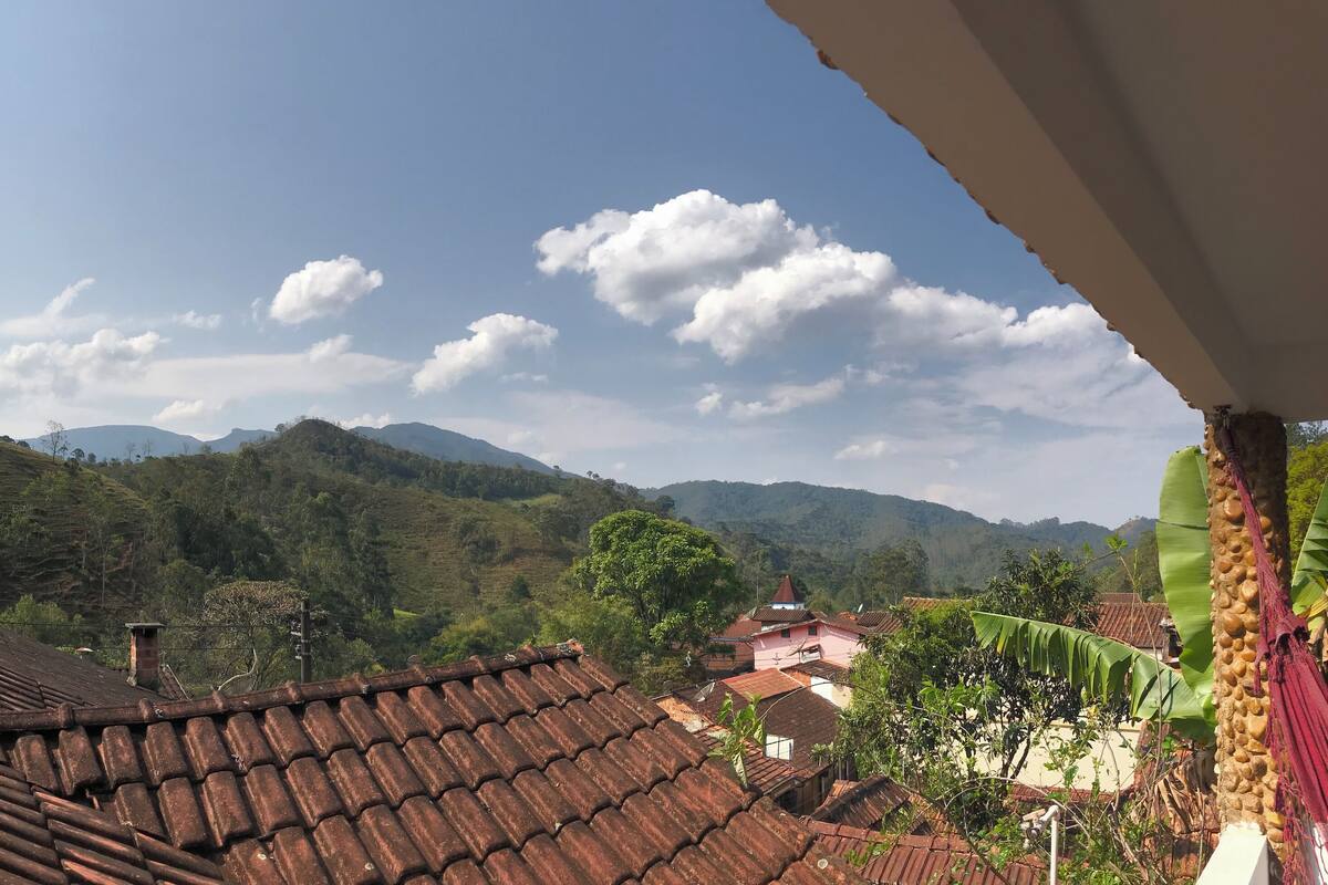 A view of terraced hills with traditional buildings, a clear sky, and a satellite dish on a roof.