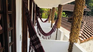 A corridor with a hammock, white walls, and a tiled floor. - Pousada Cantinho da Montanha (Itatiaia)