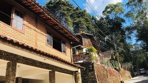 A building with a stone facade, a tiled roof, and a sign advertising apartments for rent. - Pousada Cantinho da Montanha (Itatiaia)