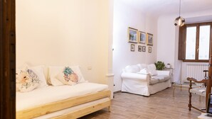 A cozy room with a wooden bed, a white sofa, and a wooden floor.