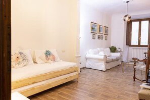 Una habitación acogedora con una cama de madera, un sofá blanco y suelo de madera.