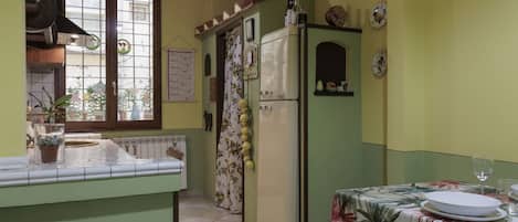 A kitchen with a window, a refrigerator, and a dining table set for two.