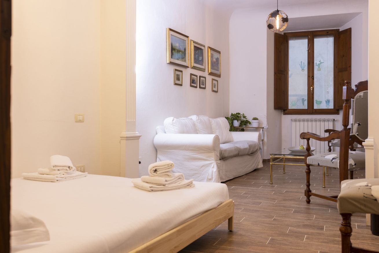 Une chambre à coucher avec un lit, une chaise, une petite table et une fenêtre avec des rideaux.
