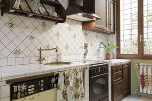 A kitchen with a tiled backsplash, a sink, a stove, and wooden cabinets. - San Niccolò Elegant Apartment (Firenze)