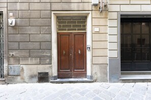 A building facade with a double wooden door, a metal grate, and a small window.