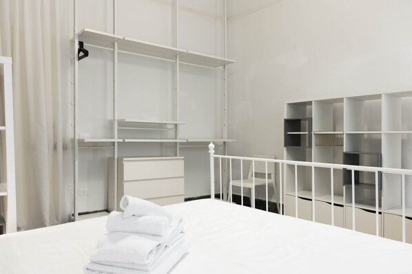 A hotel room with a bed, a white wardrobe, and a seating area with a chair.