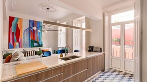 Una cucina moderna con un'isola grande, un quadro astratto dai colori vivaci e un pavimento in piastrelle geometriche.
