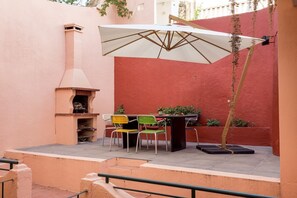 An outdoor patio with a grill, chairs, and a table. - JOIVY Exquisite apt w/ patio in Graça (Lisboa)