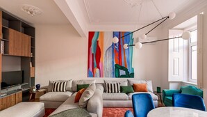 Un soggiorno moderno con un grande quadro astratto, una televisione e un'area pranzo con sedie blu.