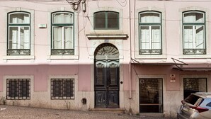 Un edificio rosa con una porta nera finemente decorata, con il numero 50, e una strada acciottolata di fronte.