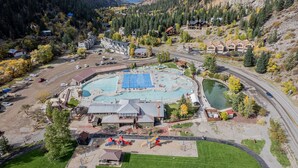 Un complexe hôtelier doté d’une grande piscine, d’un espace de jeux pour enfants et d’une route qui serpente à travers le paysage.