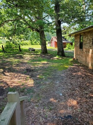 Surrounded by lush greenery, this serene outdoor space features a rustic fence and a charming brick building.